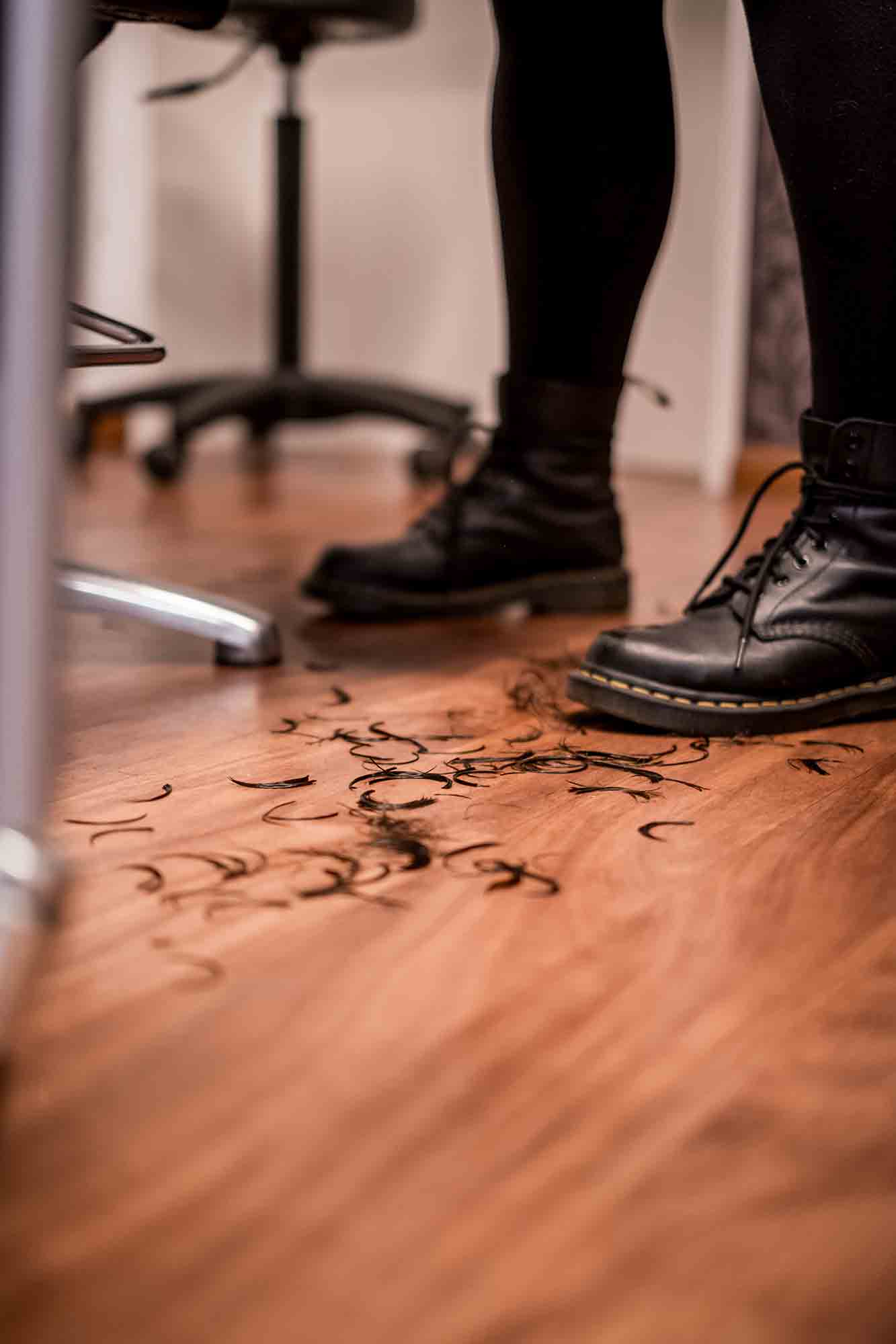 Abgeschnittene Haare auf dem Holzboden des Friseursalons