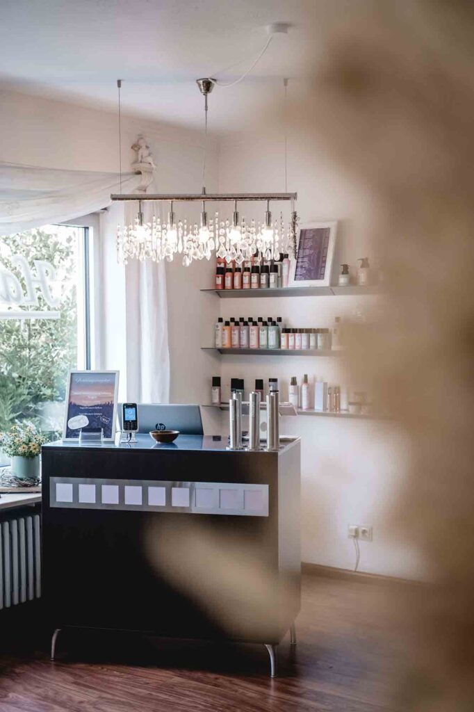 Empfangstresen mit Kronleuchter und Pflegeprodukt-Regal im Salon